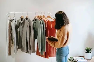 Woman standing near a modern walk‑in closet choosing neutral capsule pieces from a curated wardrobe rack